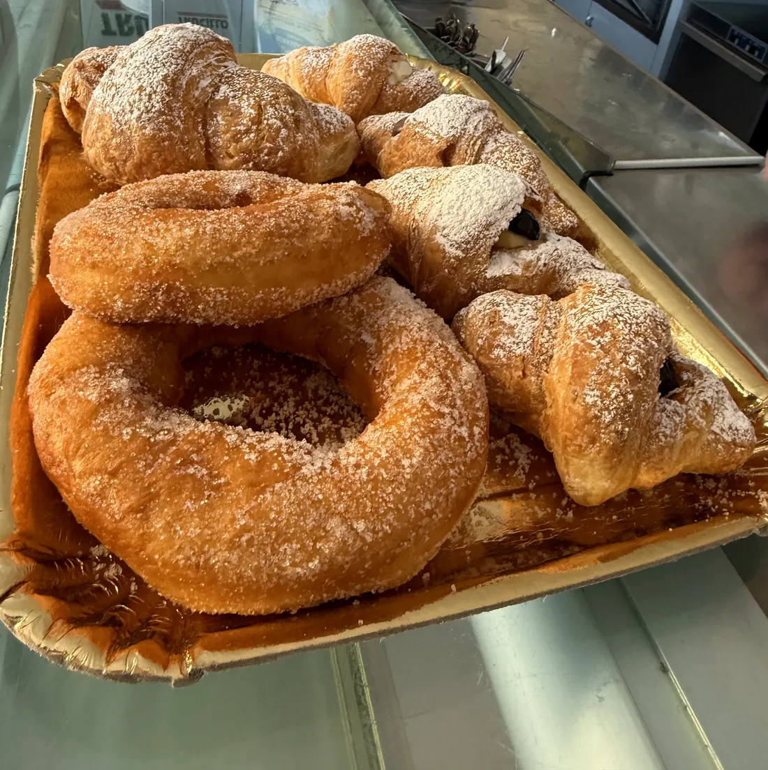 Graffe e cornetti zuccherati sul vassoio dorato