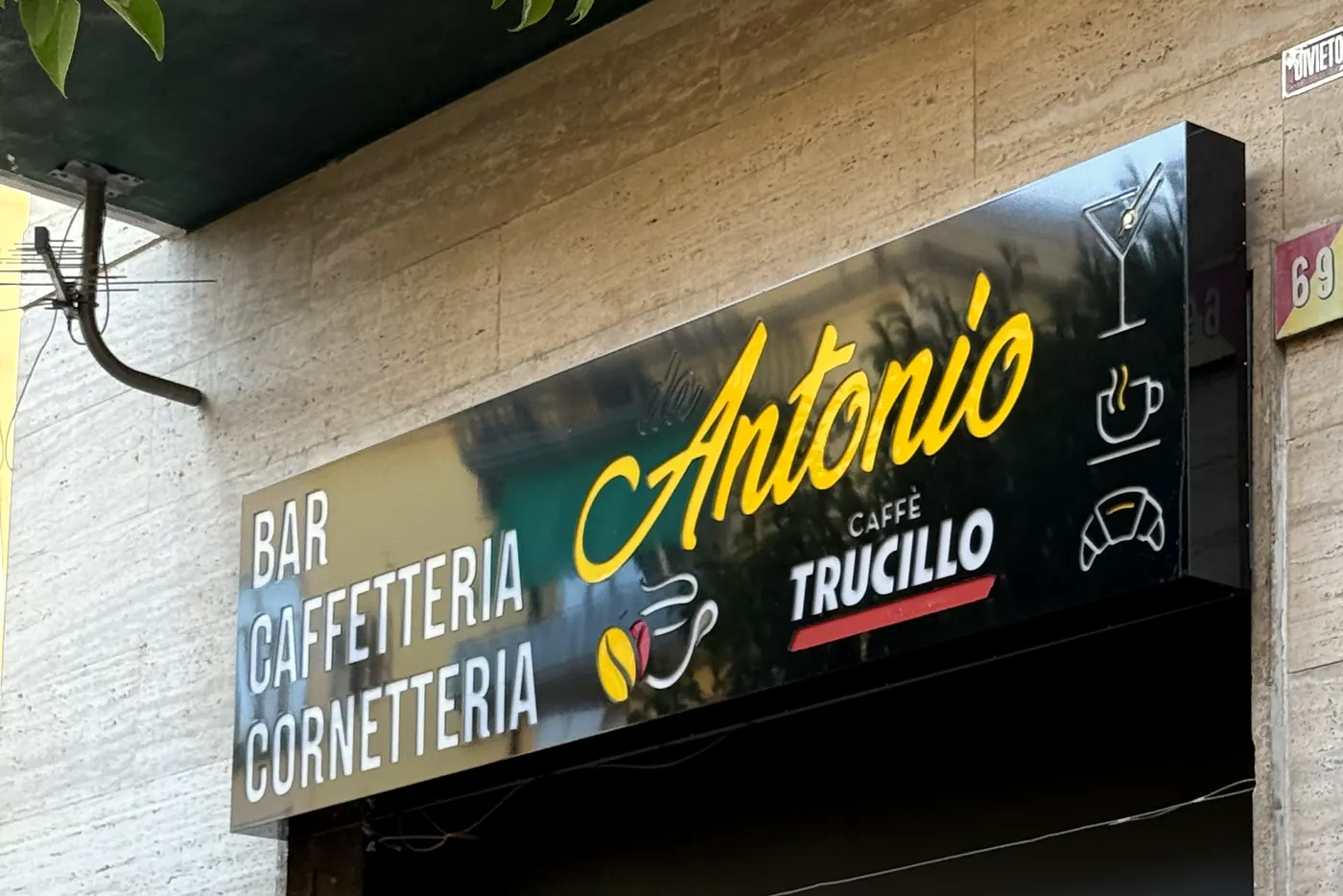 L’insegna nera e gialla del bar: Bar Caffetteria Cornetteria Antonio, caffè Trucillo